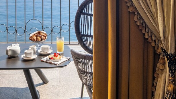 A balcony with a table set for breakfast, overlooking a body of water and distant mountains. - Grand Hotel Dino (Baveno)