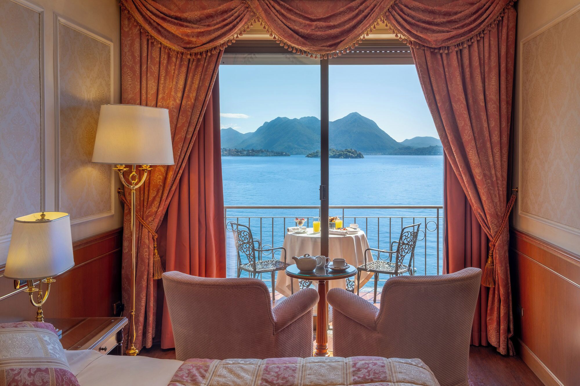 Una stanza con un letto, un tavolo con sedie e vista su un lago e montagne.