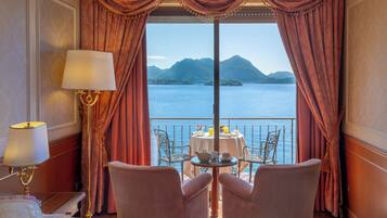 Una stanza con un letto, un tavolo con sedie e vista su un lago e montagne.