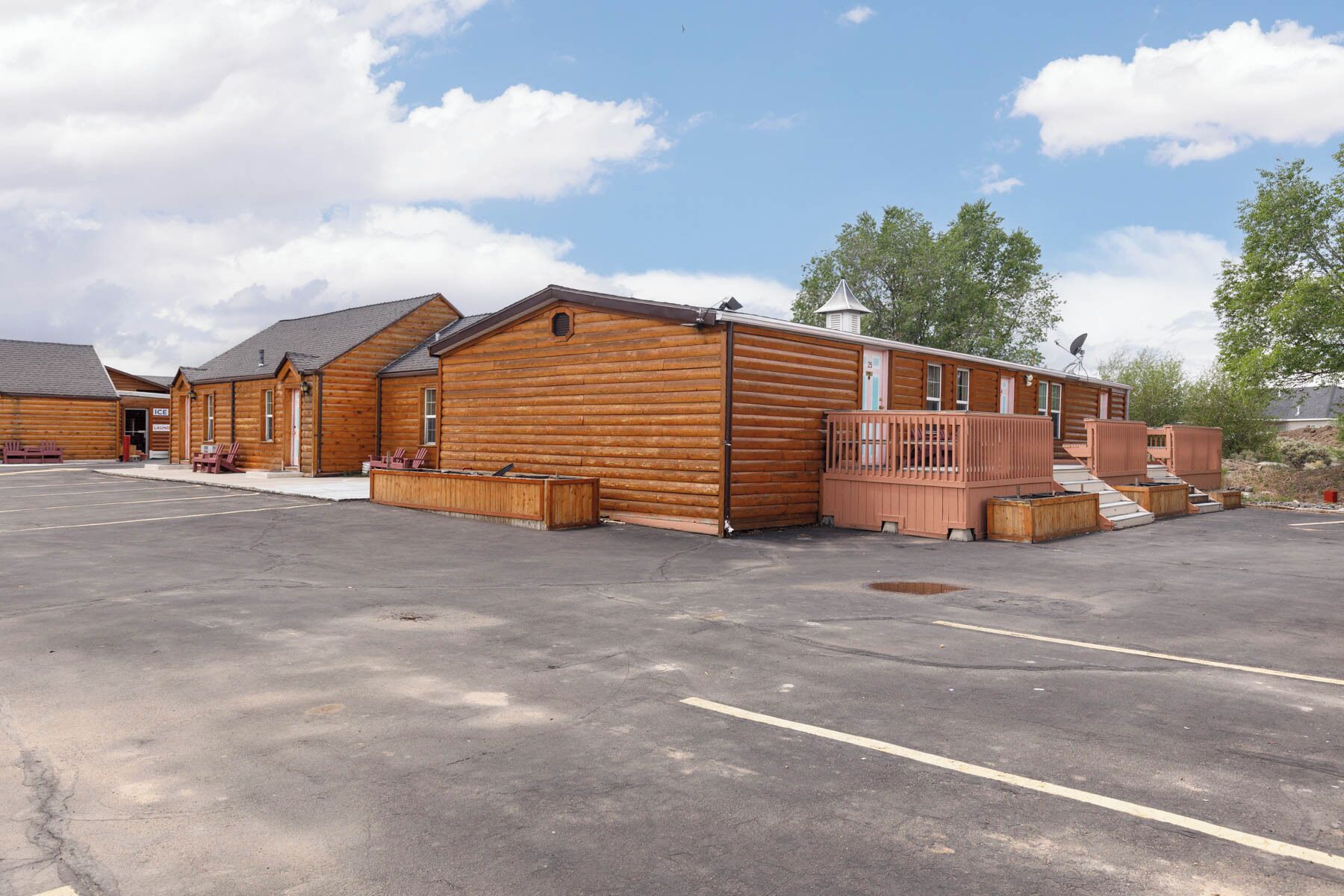 A row of log cabins with a parking lot in front.
