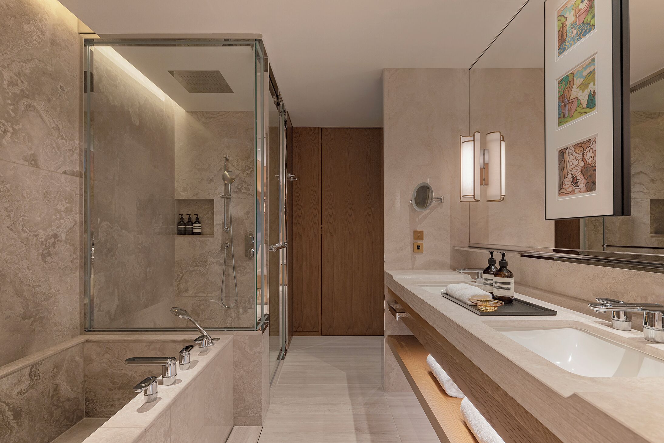 A modern bathroom with a glass-enclosed shower, two sinks, and a wooden door.