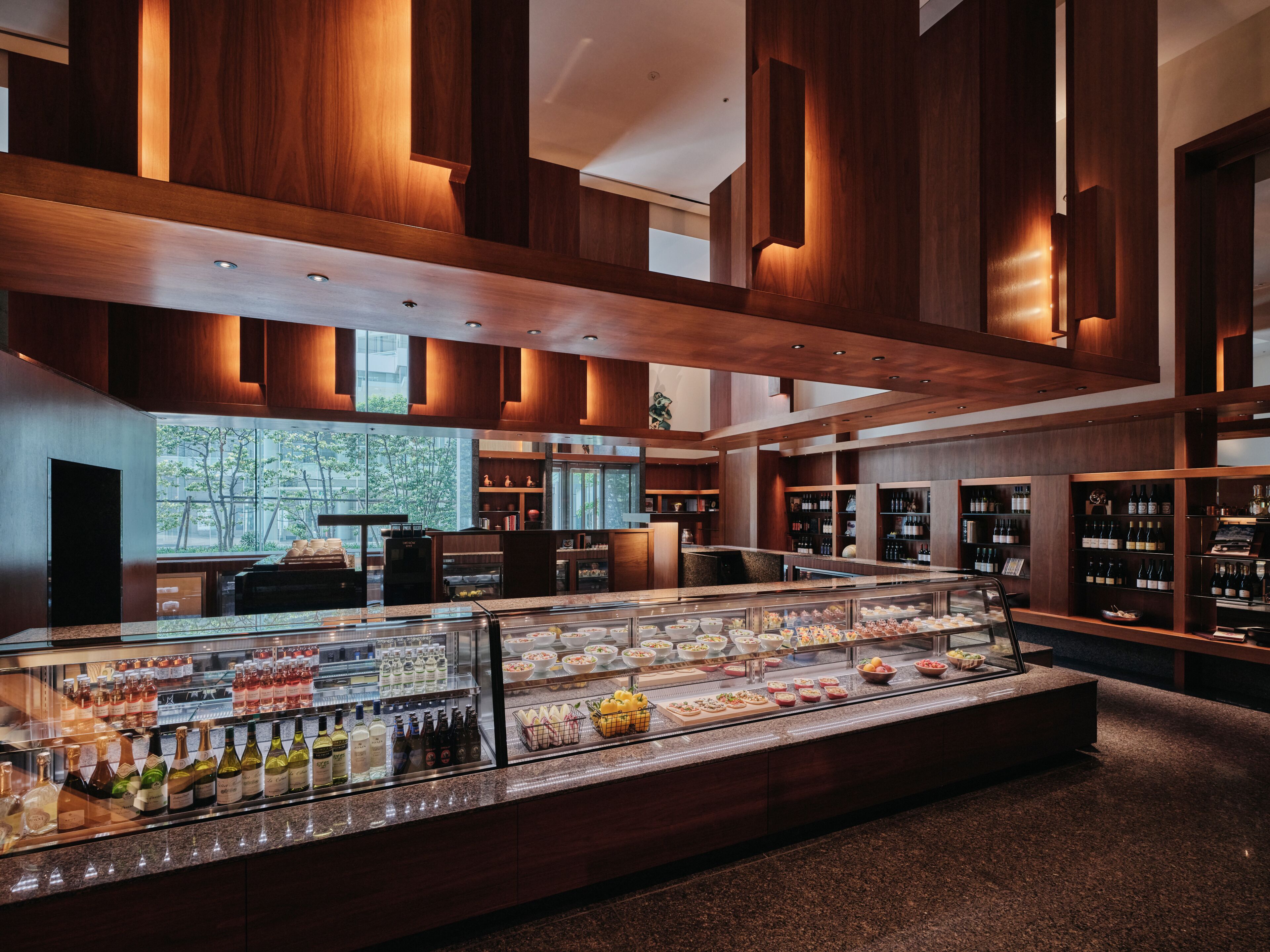 A modern bar area with a glass display case of beverages and a wine rack.