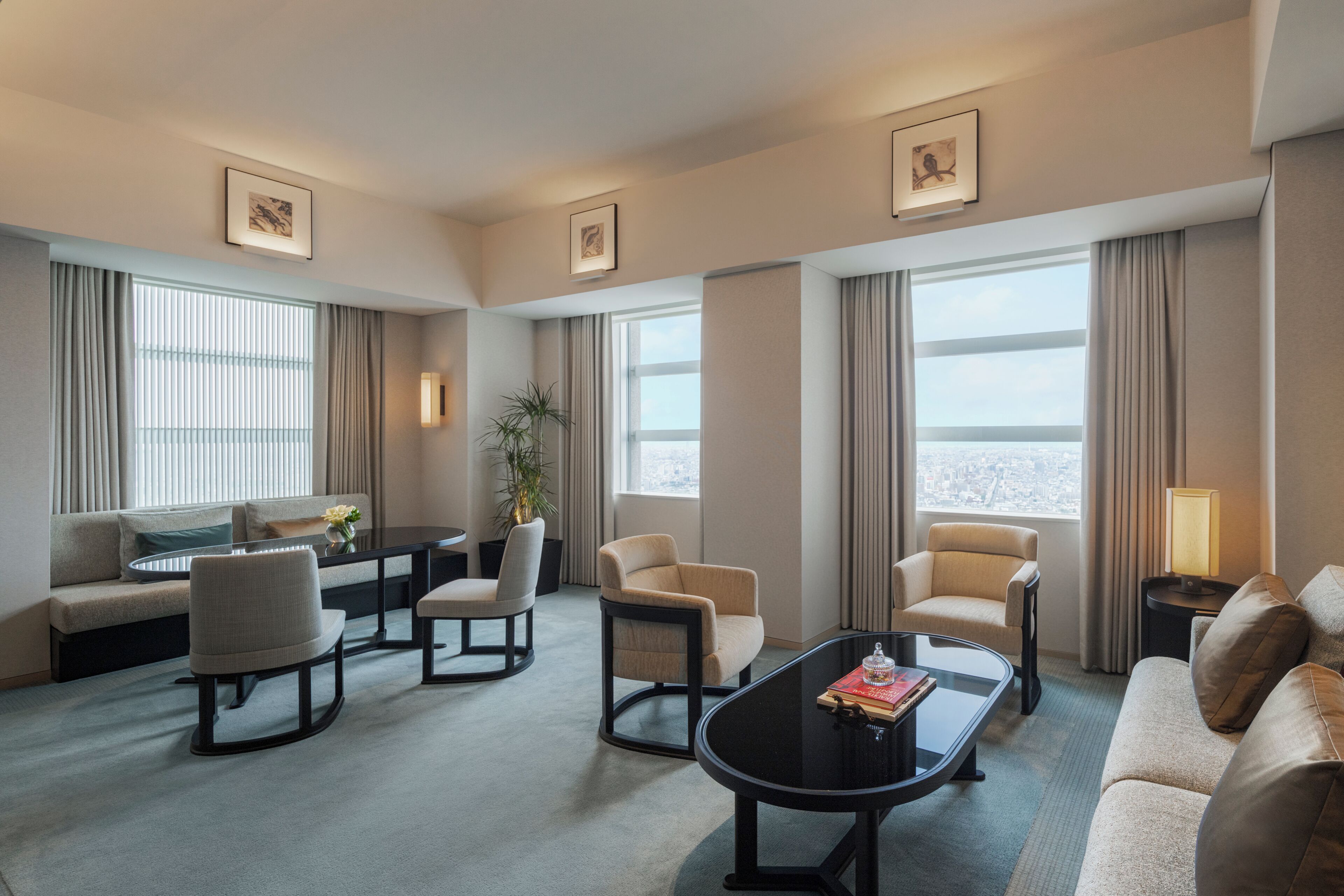 A hotel room with a sofa, chairs, a coffee table, a dining table, and a view of the city.