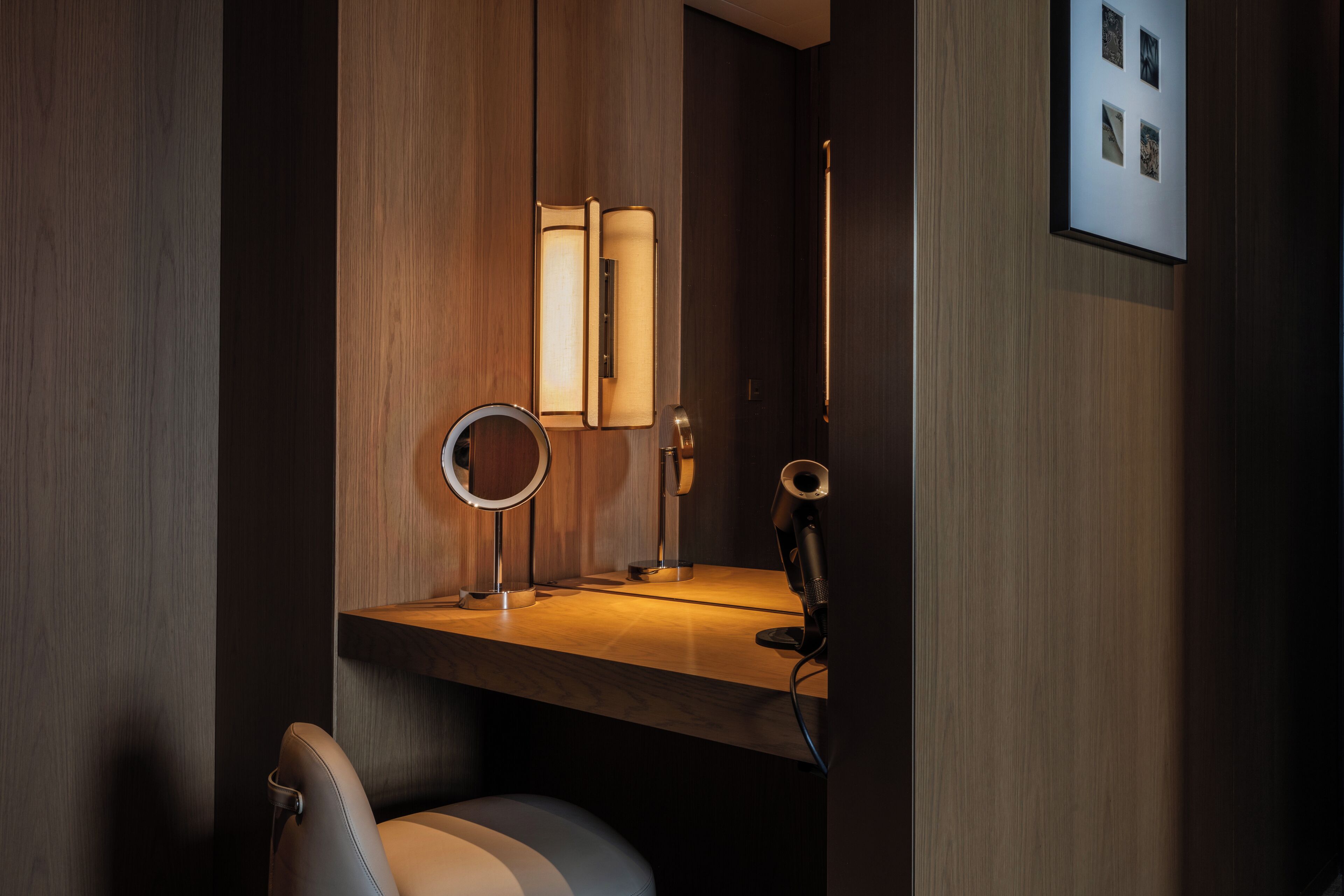 A modern bathroom with a vanity, mirror, and a chair.