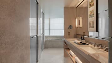 Un baño moderno con cabina de ducha de vidrio, un espejo grande y un mueble de tocador con lavamanos y perchero.
