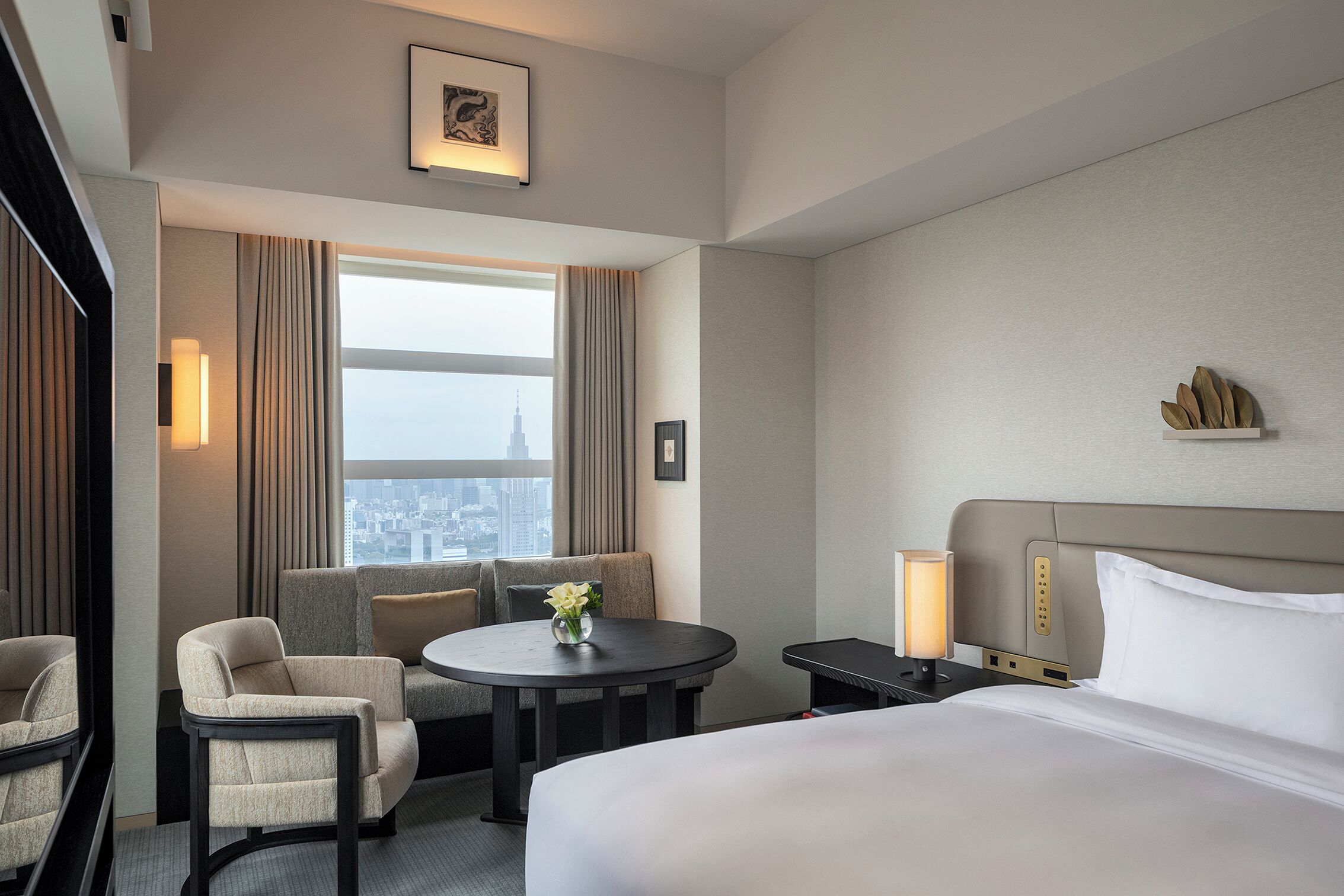 A hotel room with a bed, a round table with chairs, a nightstand, and a window with curtains.