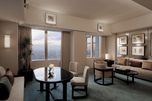 A modern hotel room with a large window, a sofa, a coffee table, and a small side table. - Park Hyatt Tokyo (Tokyo)