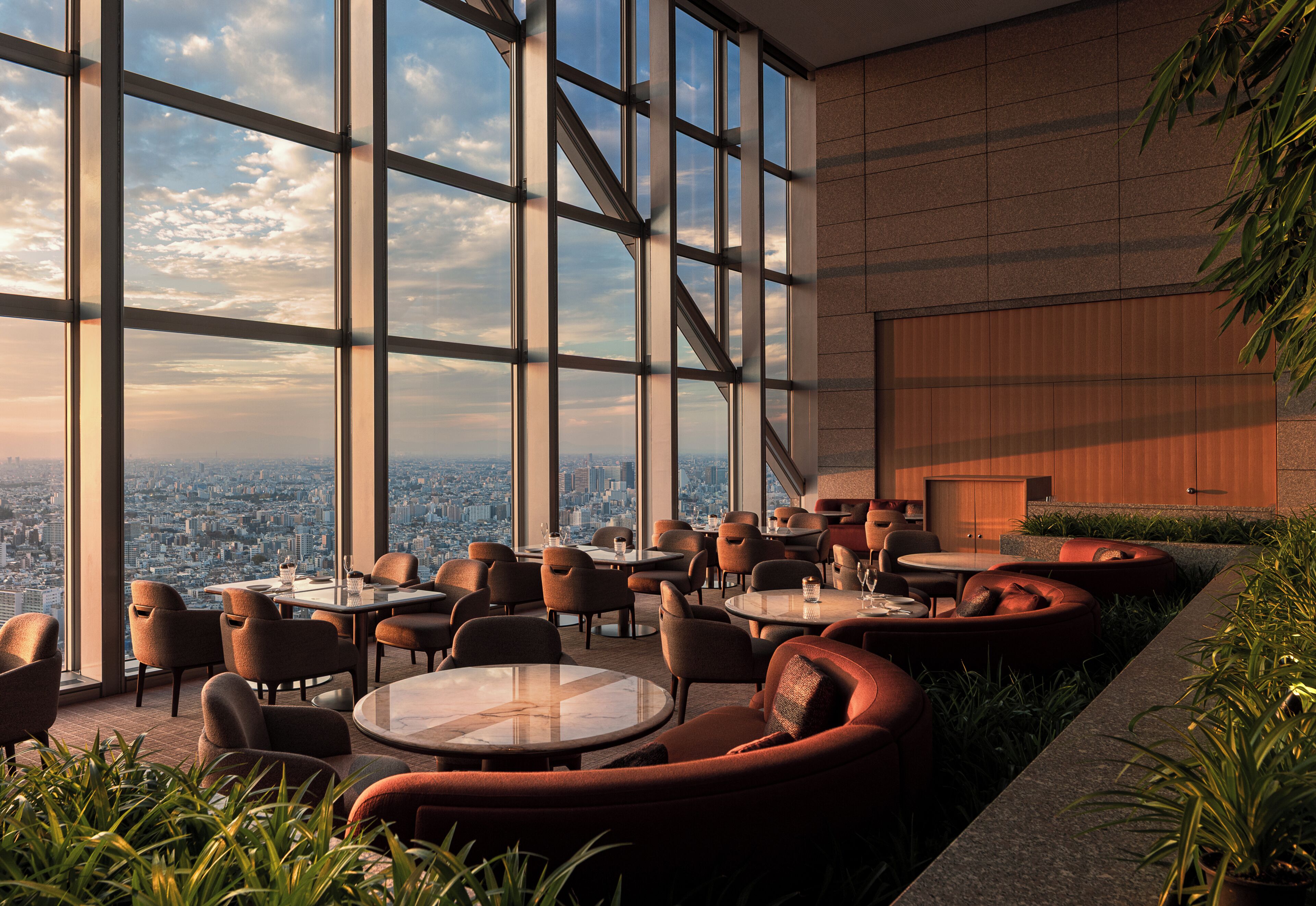 A modern interior with large windows, round tables, and comfortable seating.