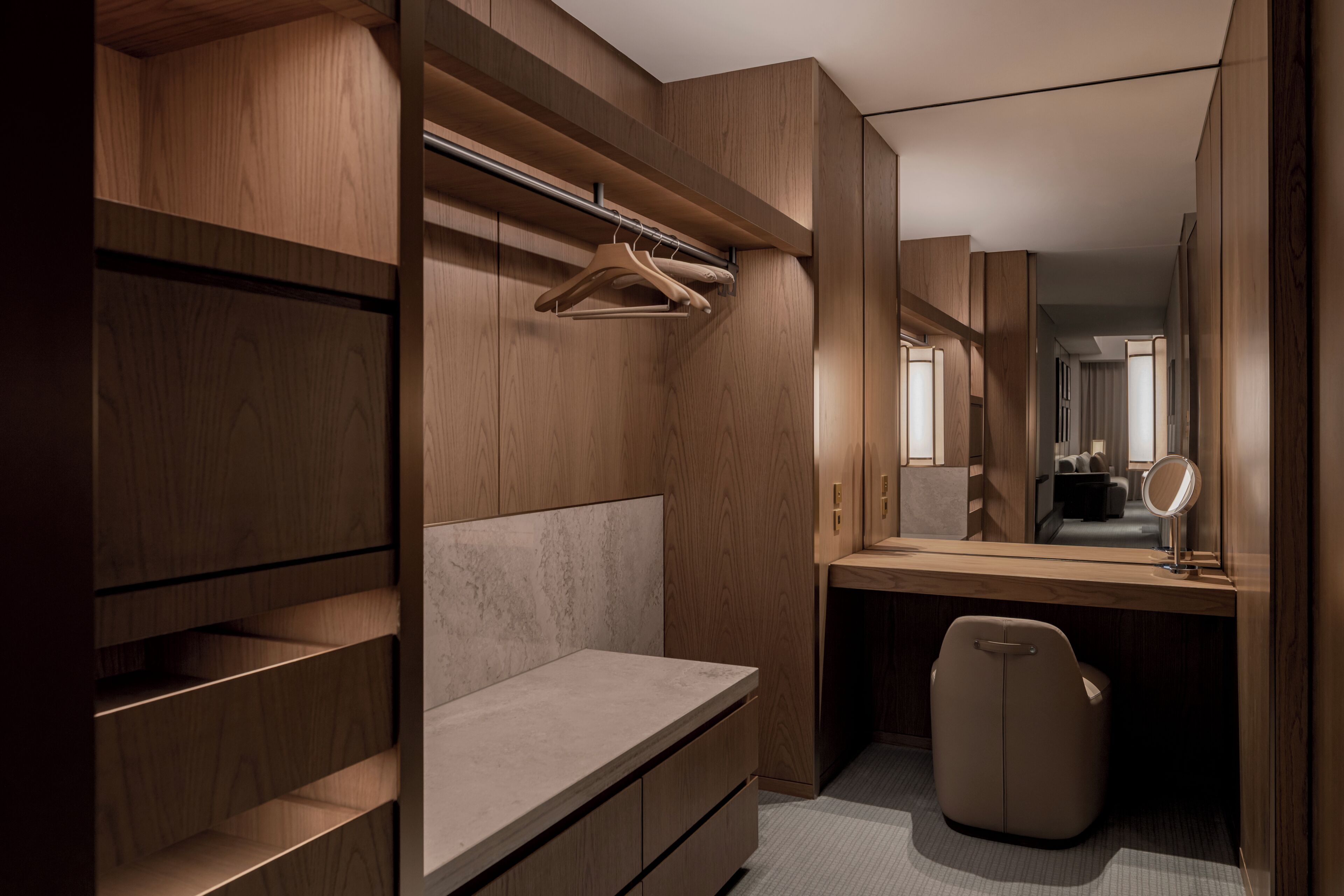 A modern walk-in closet with wooden shelving, a bench, a mirror, and a hanging rack.