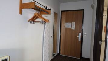 A hallway with a wooden door, a coat rack, and a digital clock.