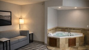 A modern bathroom with a freestanding bathtub, a sofa, and a small table. - AmericInn by Wyndham Dickinson (Dickinson)