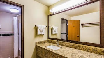 A bathroom with a granite countertop, a white sink, and a large mirror.
