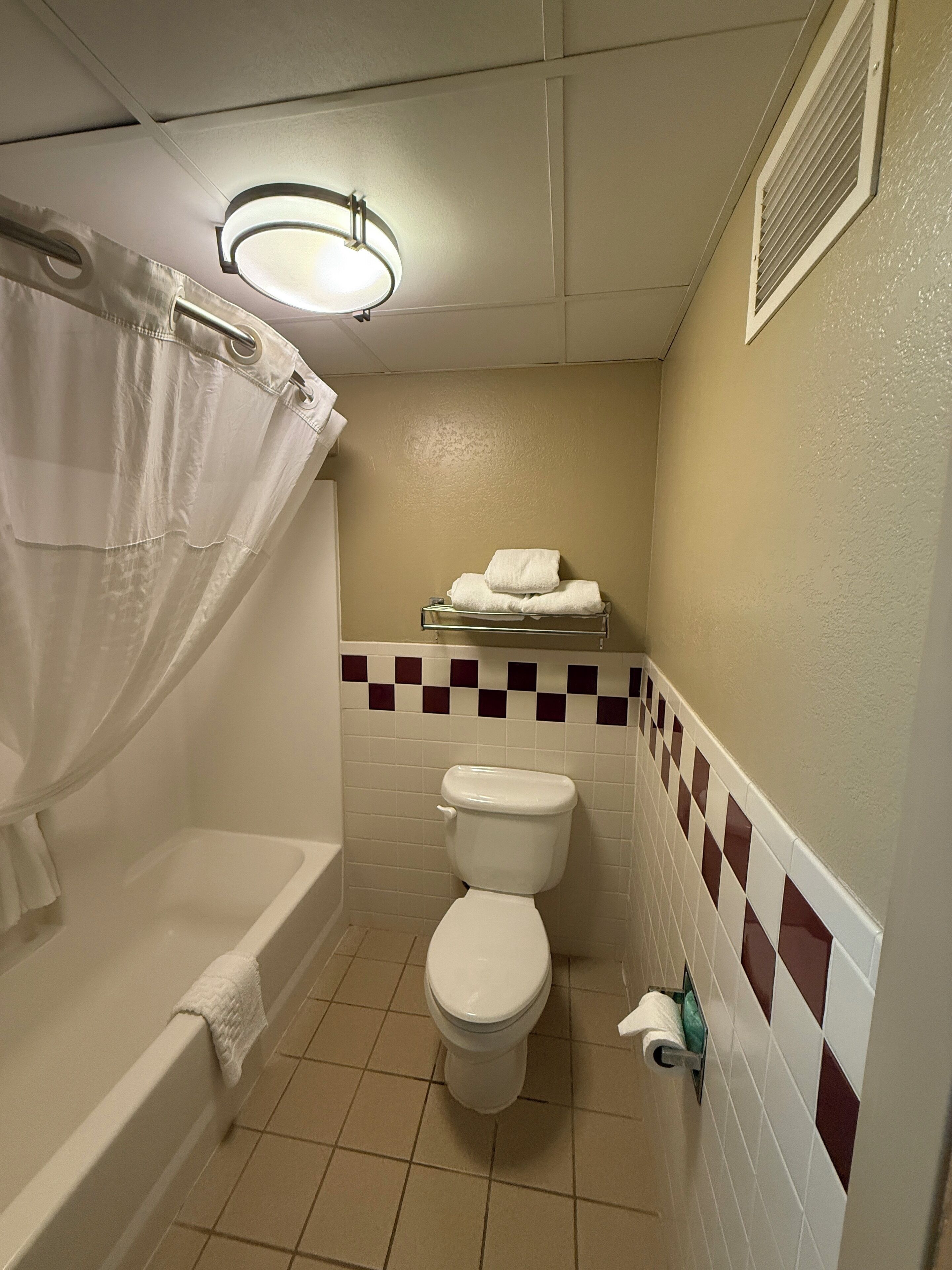 Un baño pequeño con bañera, inodoro y un perchero para toallas.