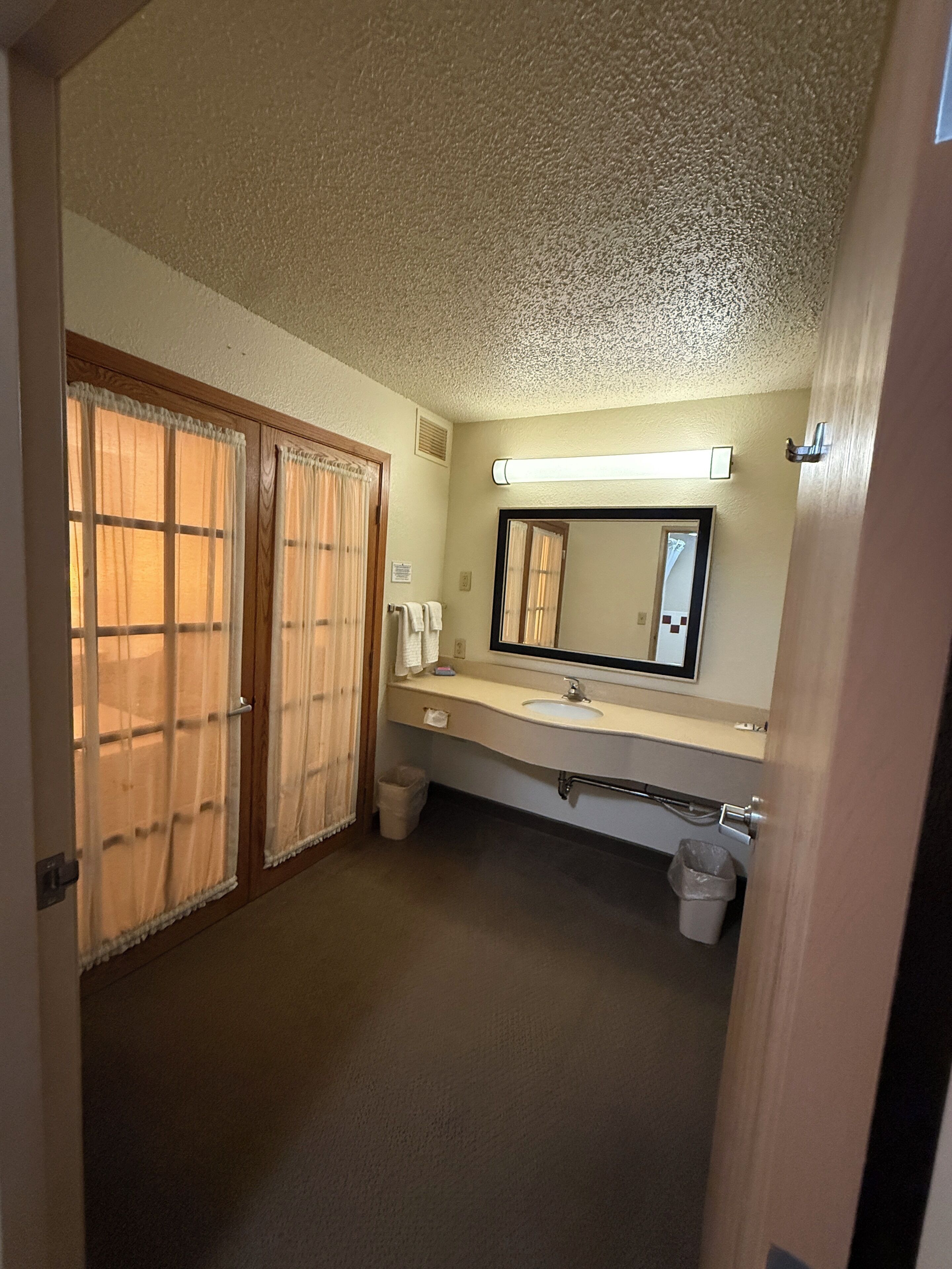 A hotel bathroom with a sink, mirror, and a towel rack.