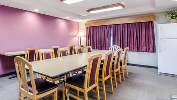 A conference room with a long table and chairs, purple walls, and a window with curtains.