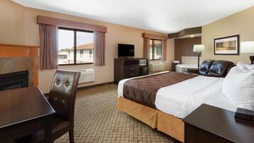 A hotel room with a bed, a desk, a chair, a television, a dresser, and a window with curtains.