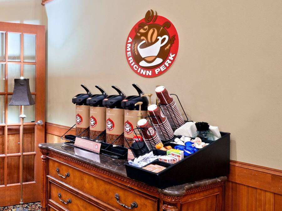 A coffee station with multiple coffee dispensers, a coffee urn, and a variety of coffee cups and mugs.