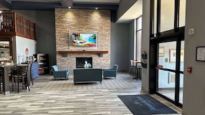 Un vestíbulo con pared de piedra, chimenea, televisor y zona de estar.