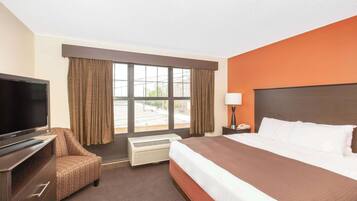 A hotel room with a bed, a TV, a chair, a window, and a nightstand.