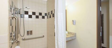 Une salle de bain d’hôtel équipée d’une douche, d’une barre d’appui et d’un porte-serviettes.