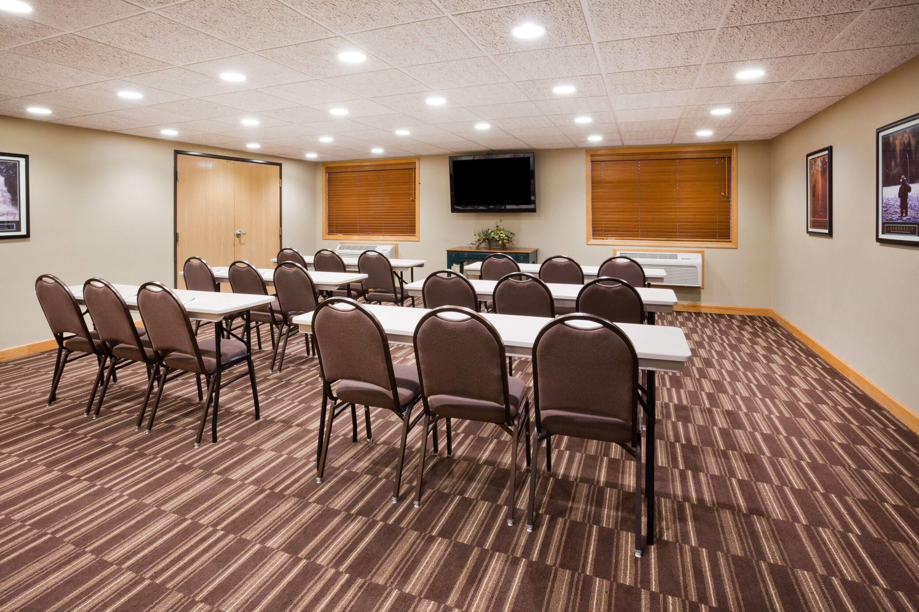 Un salón de conferencias con una larga mesa, sillas, un televisor y una puerta.