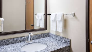 A bathroom with a granite countertop sink, a mirror, and a towel rack with white towels.