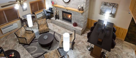 Amplia sala de estar con chimenea, asientos y un reloj en la pared.