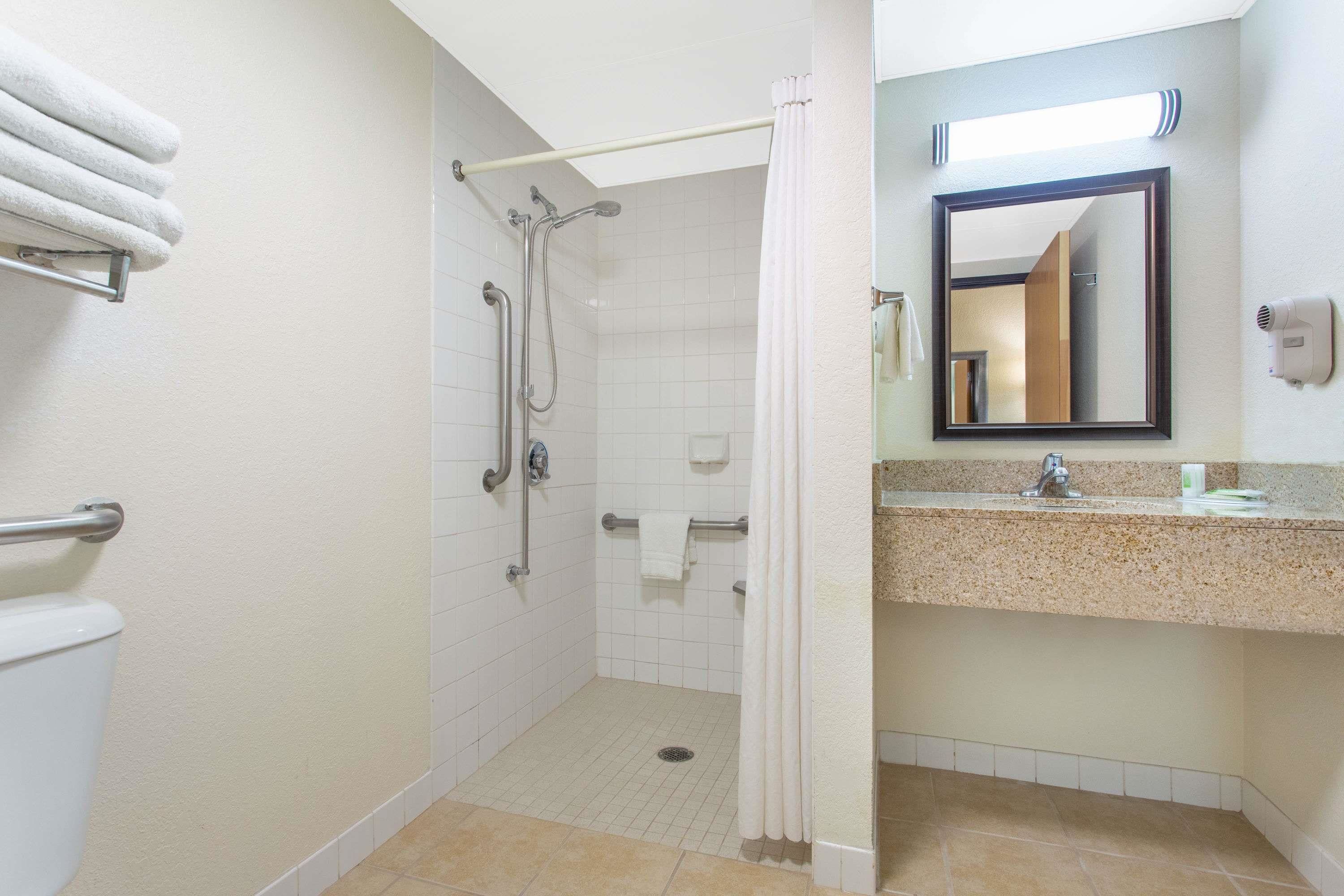 A hotel bathroom with a shower, toilet, and sink.