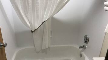 Un baño con bañera, cortina de ducha y retrete.