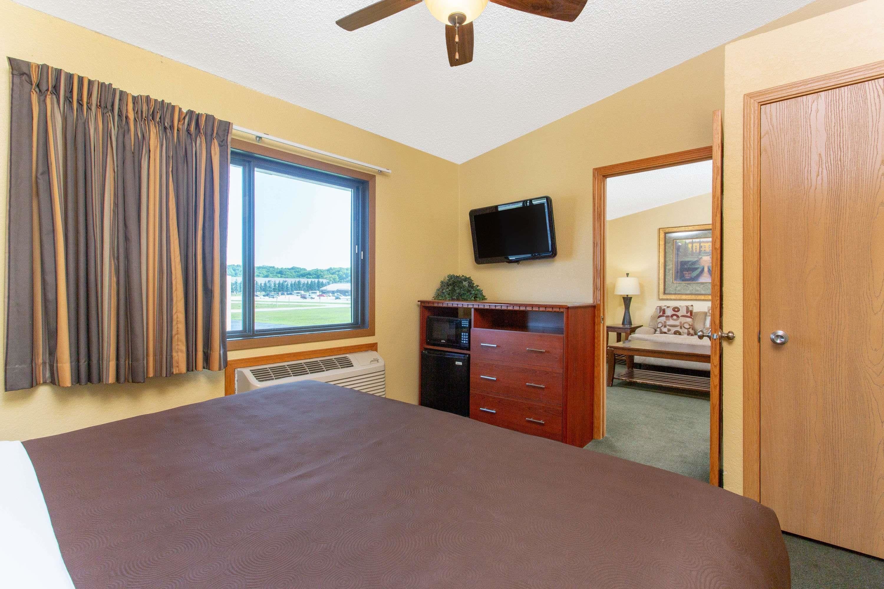 Un dormitorio con una cama grande, ventilador de techo, televisión, microondas y vistas al exterior.