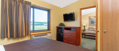 Un dormitorio con una cama grande, ventilador de techo, televisión, microondas y vistas al exterior.