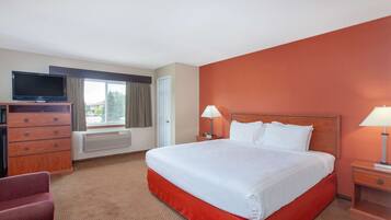 A hotel room with a large bed, a TV on a wooden dresser, two bedside lamps, and a window with curtains.