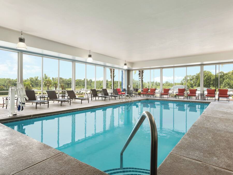 A swimming pool with lounge chairs and a view of the outdoors.