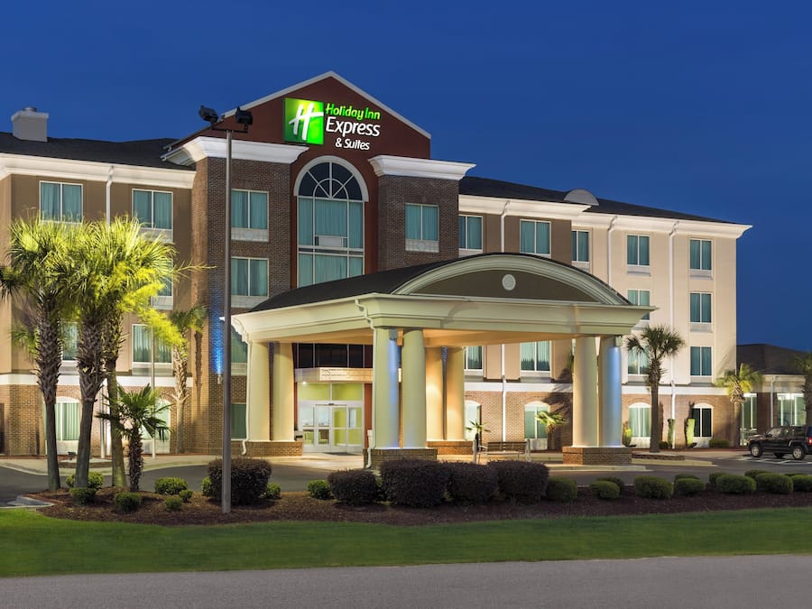 A Holiday Inn Express & Suites hotel with a covered entrance, multiple windows, and a parking lot.