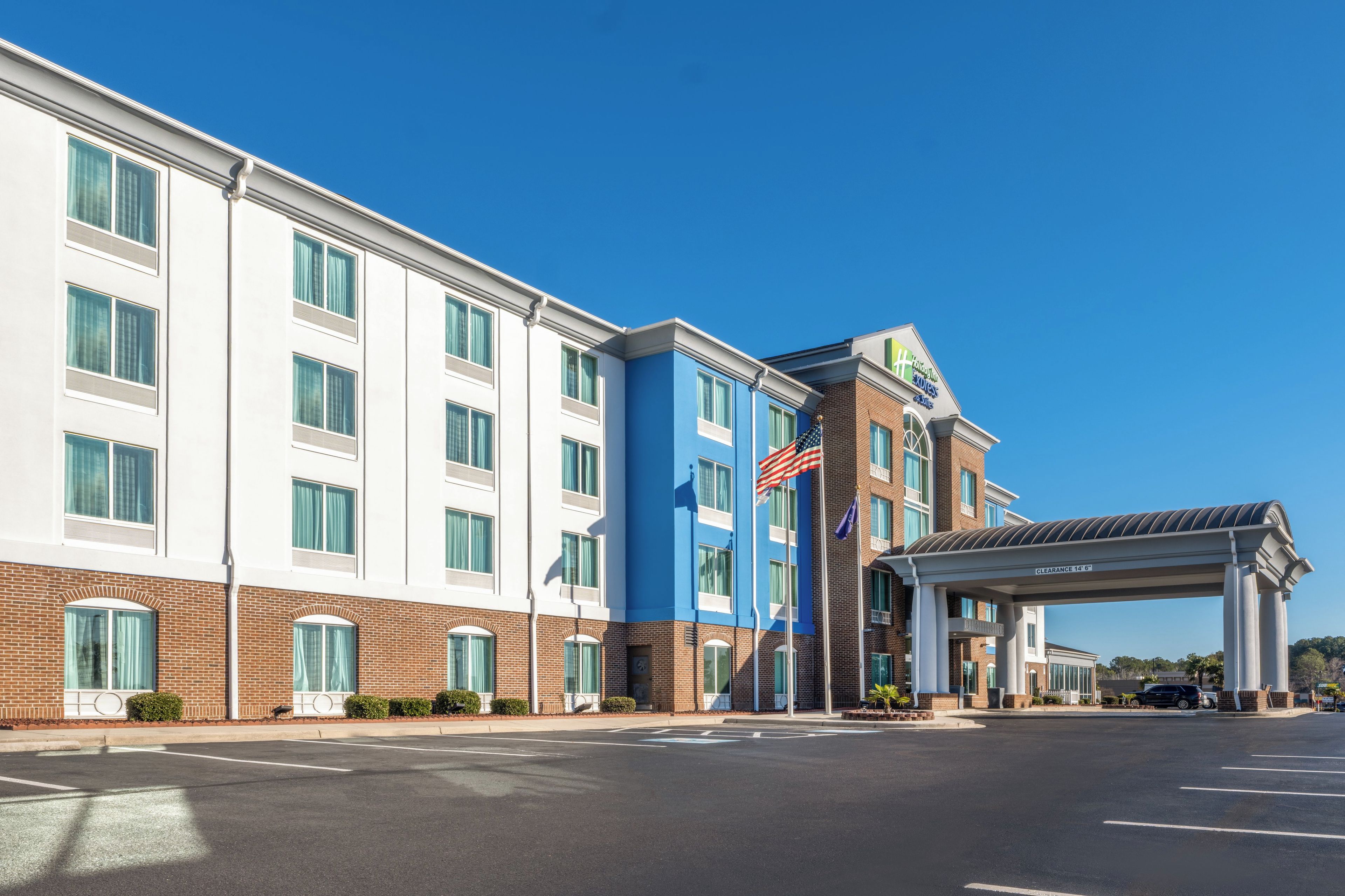 A hotel with a modern design, featuring a prominent entrance with a covered walkway and an American flag.