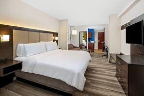 A hotel room with a large bed, a desk, a chair, a TV, and a mirror.