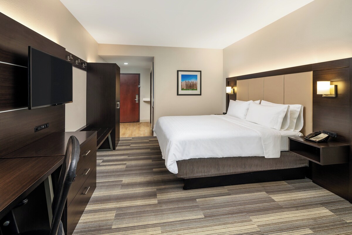 A hotel room with a bed, a TV, a desk, and a nightstand with a phone.