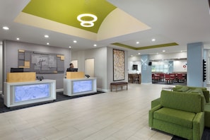 Een hotel receptie met modern design, inclusief een receptiebalie, zithoek en een eetgedeelte.