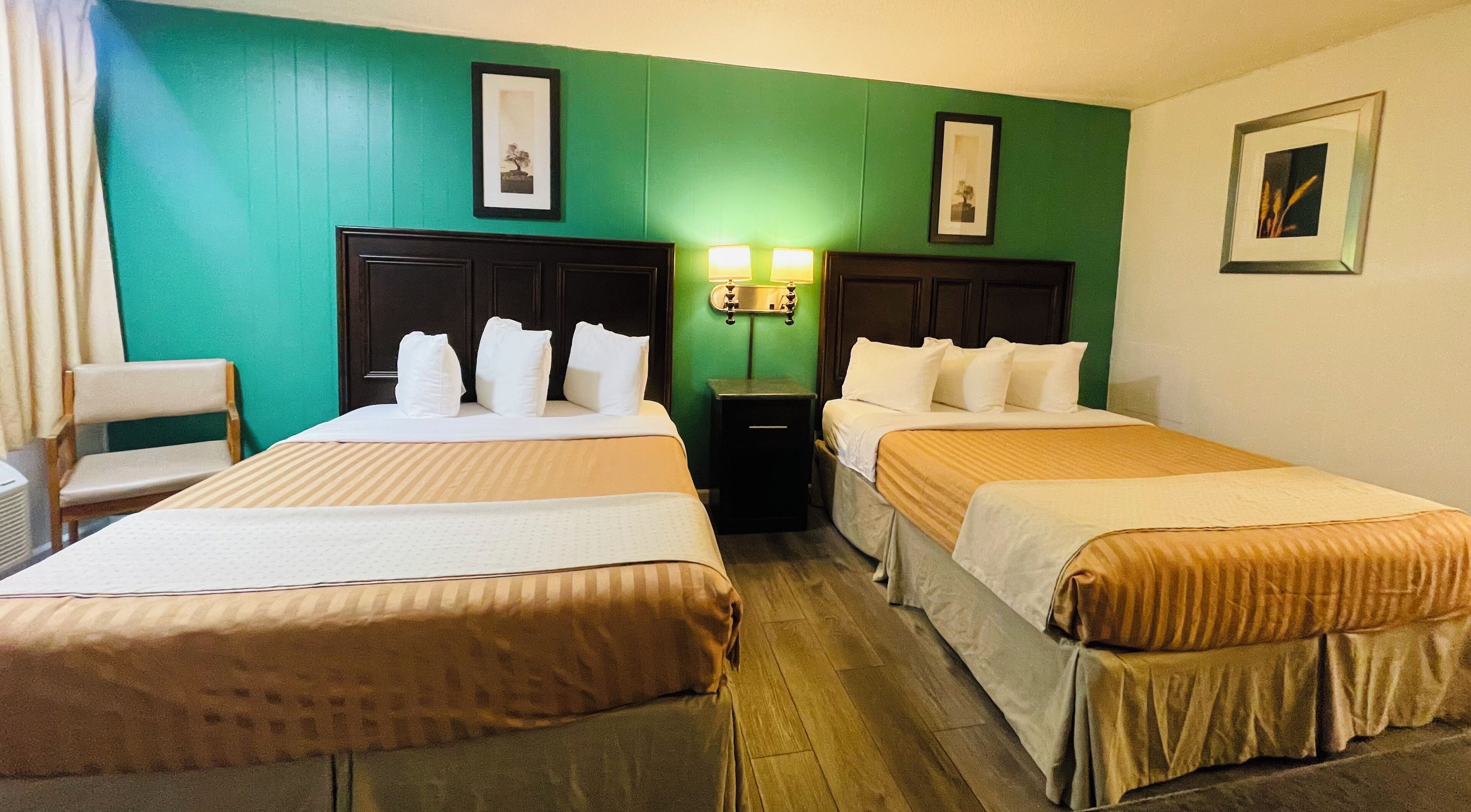 A hotel room with two beds, a chair, a nightstand, and wall-mounted lamps.