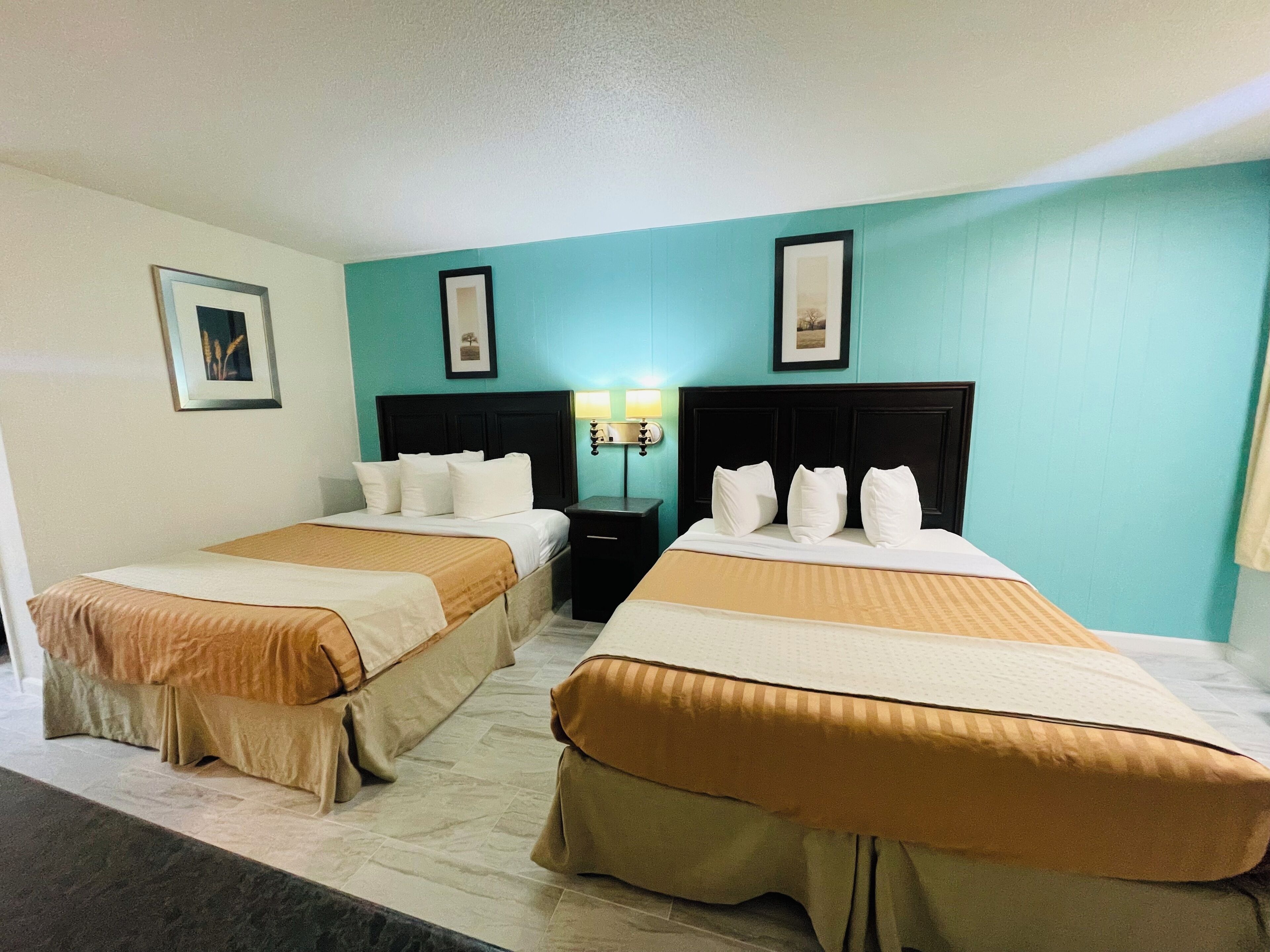 Una habitación de hotel con dos camas, una mesita de noche y una lámpara fijada a la pared.