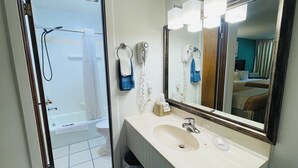 Un baño con ducha, lavamanos y espejo.