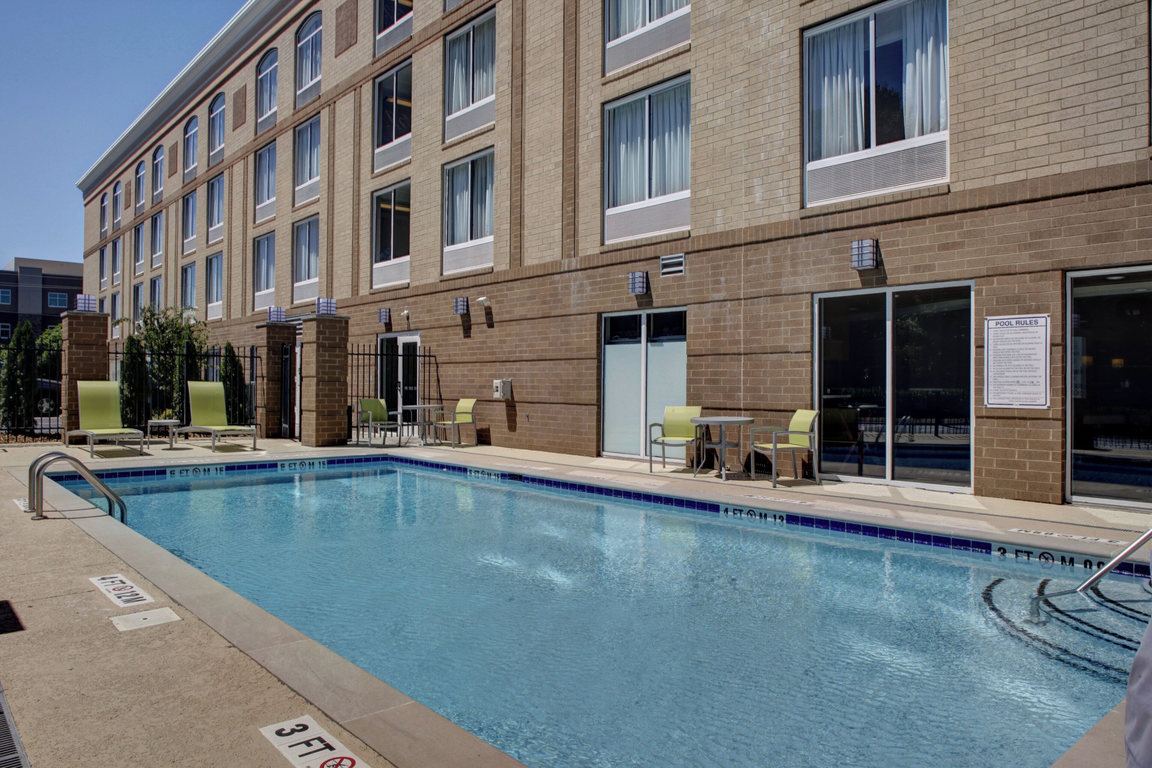 Hotel com piscina, área de estar ao ar livre e placa com as regras da piscina.