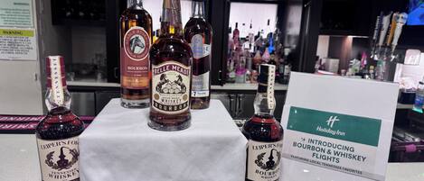 Zona de bar con varias botellas de whiskey y un cartel que promociona favoritos locales de Tennessee.