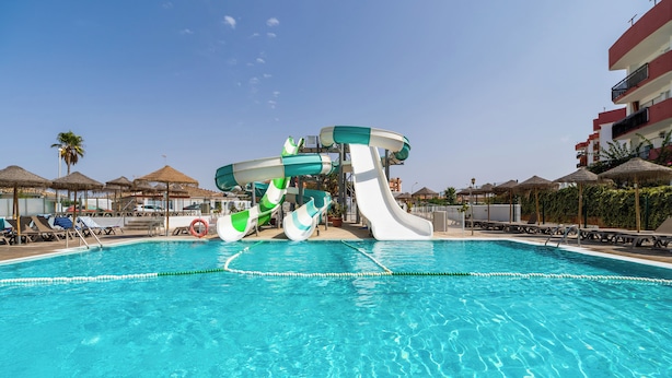 A swimming pool with a water slide and lounge chairs.