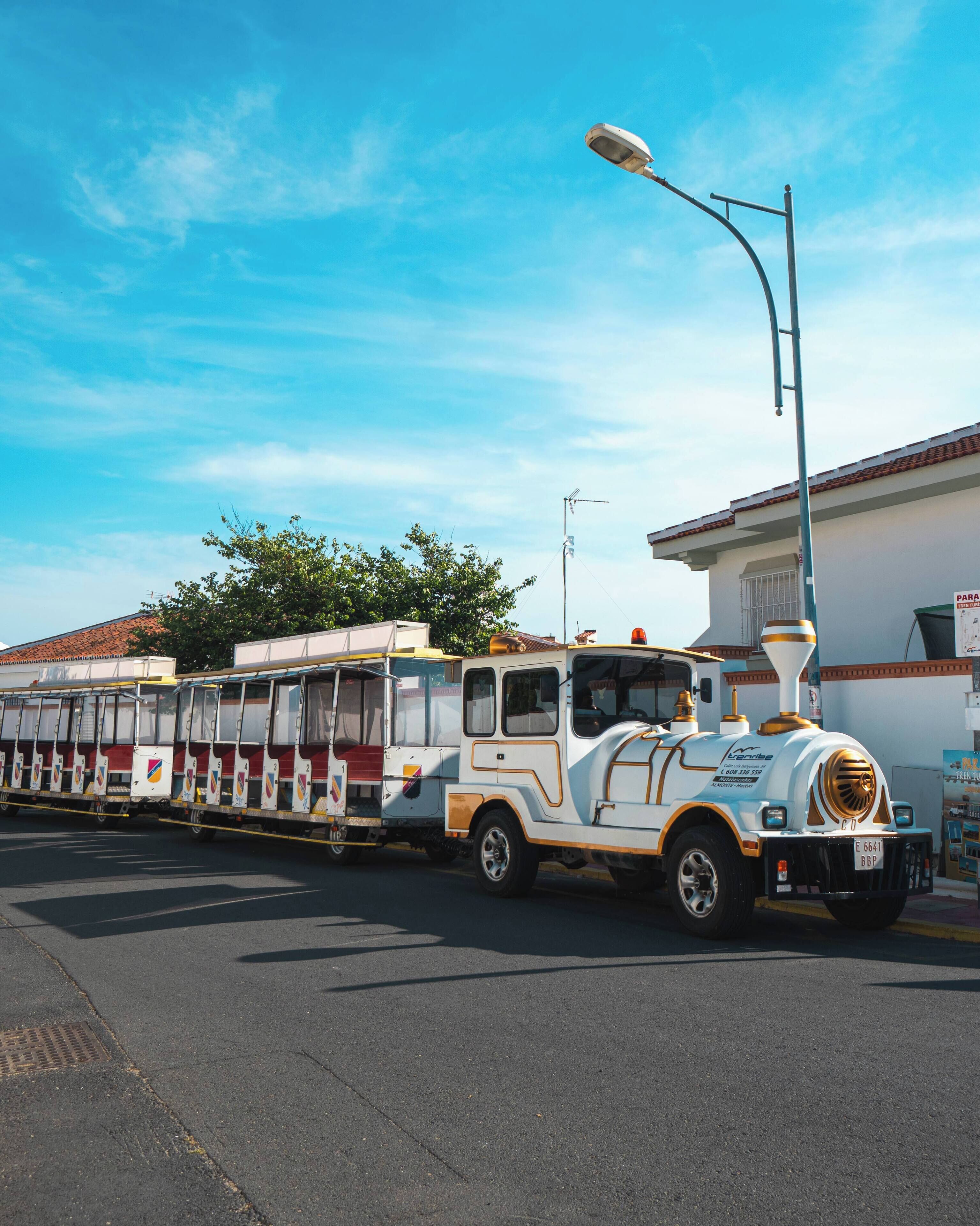 Un autobus bianco e giallo con un motore grande, parcheggiato su una strada sotto un cielo azzurro intenso.