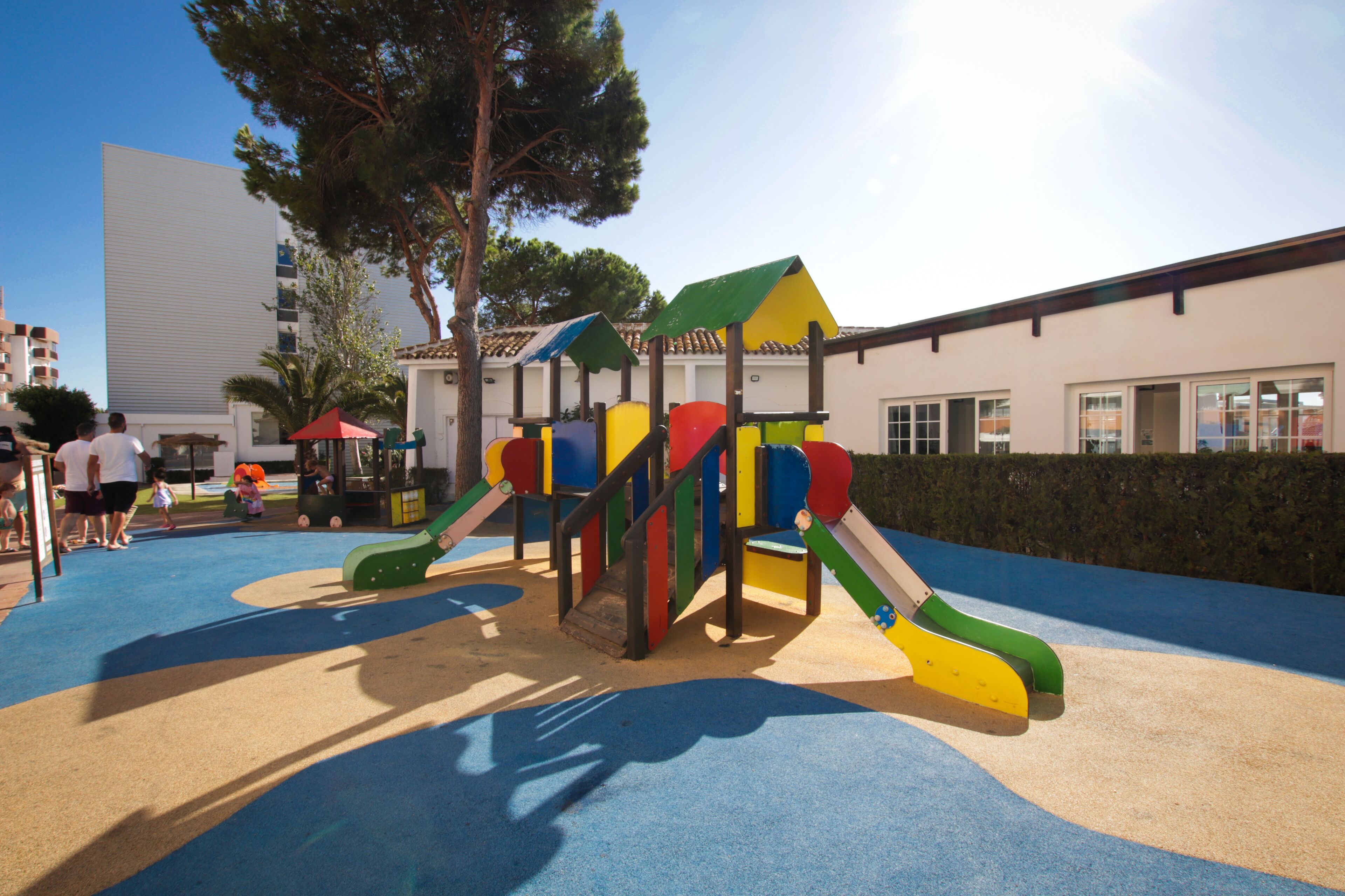 Un parque infantil con estructuras de juego coloridas y una zona de arena.