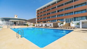 Una piscina al aire libre, sillones reclinables de piscina