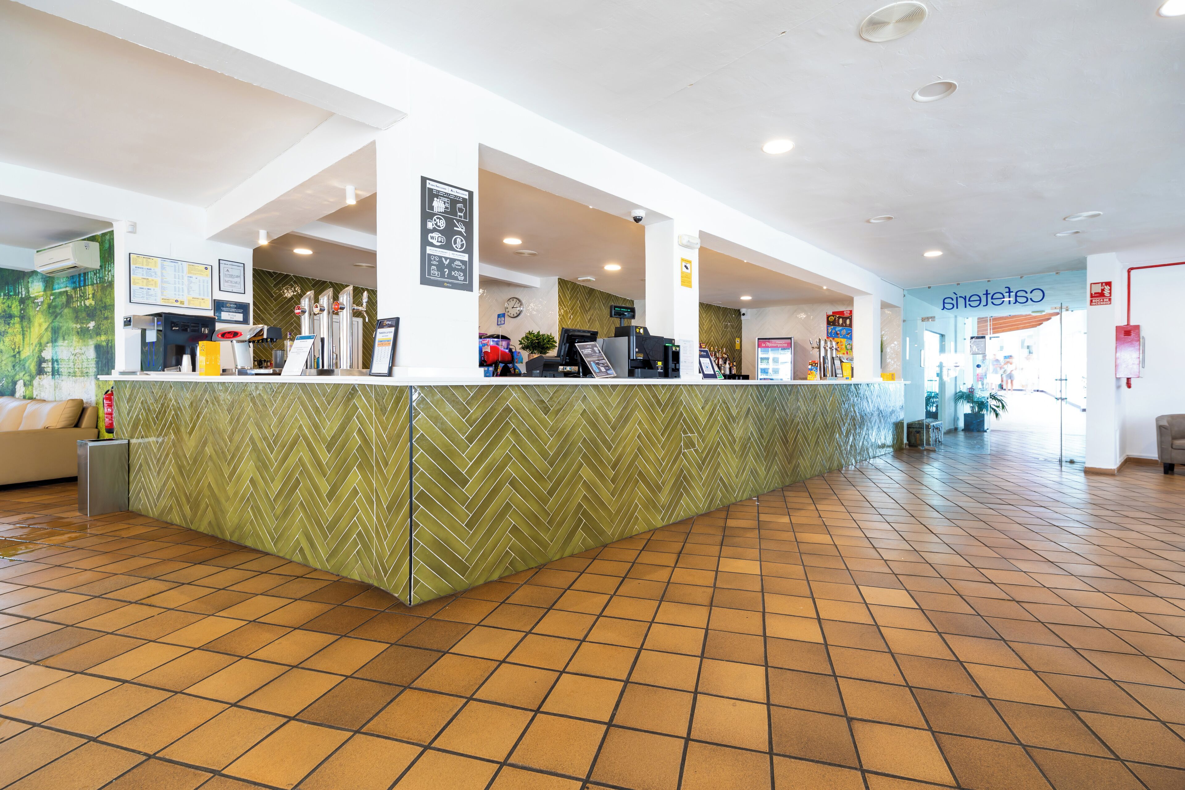 A reception area with a herringbone-patterned counter, a coffee machine, and a clock on the wall.