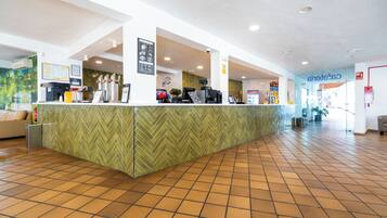 A reception area with a herringbone-patterned counter, a coffee machine, and a clock on the wall.