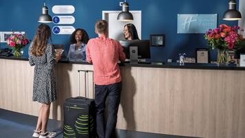 Un mostrador de recepción de hotel con una pantalla digital, un letrero de 'Holiday Inn Express' y un cartel que indica 'Cambio'.